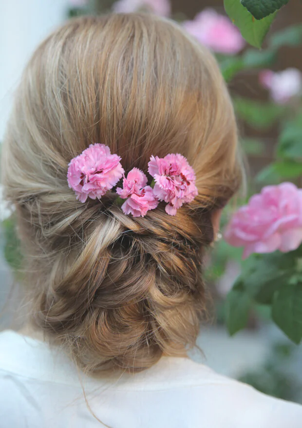 Bruid met roze bloemen in bruidskapsel op trouwdag