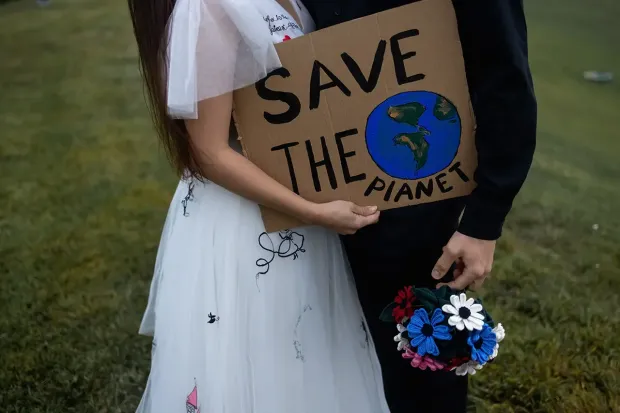 bruidspaar met save the planet bord op duurzame bruiloft