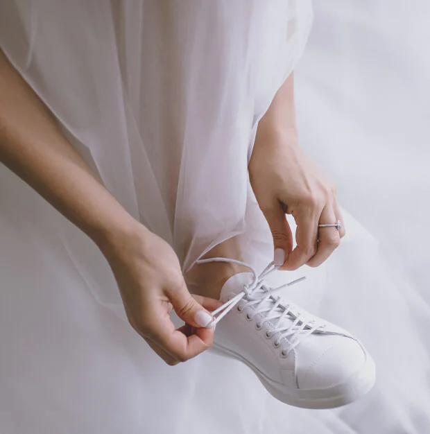 Witte bruidssneakers onder trouwjurk als originele en comfortabele bruidsschoen