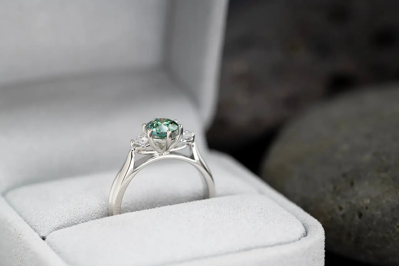 een prachtige verlovingsring met een groene steen in een ringdoosje